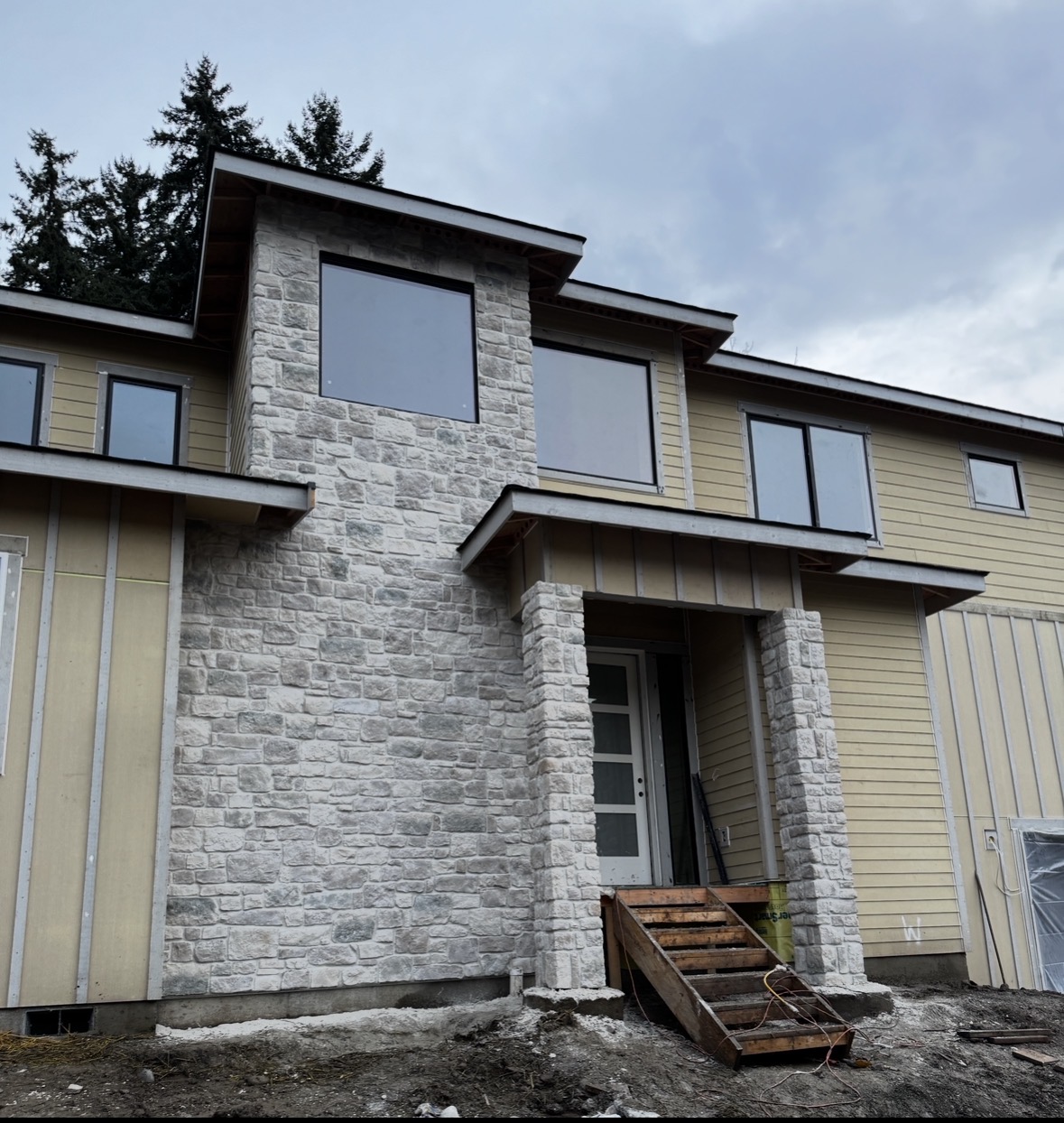 Modern home entry with hand-laid stacked stone veneer columns and chimney