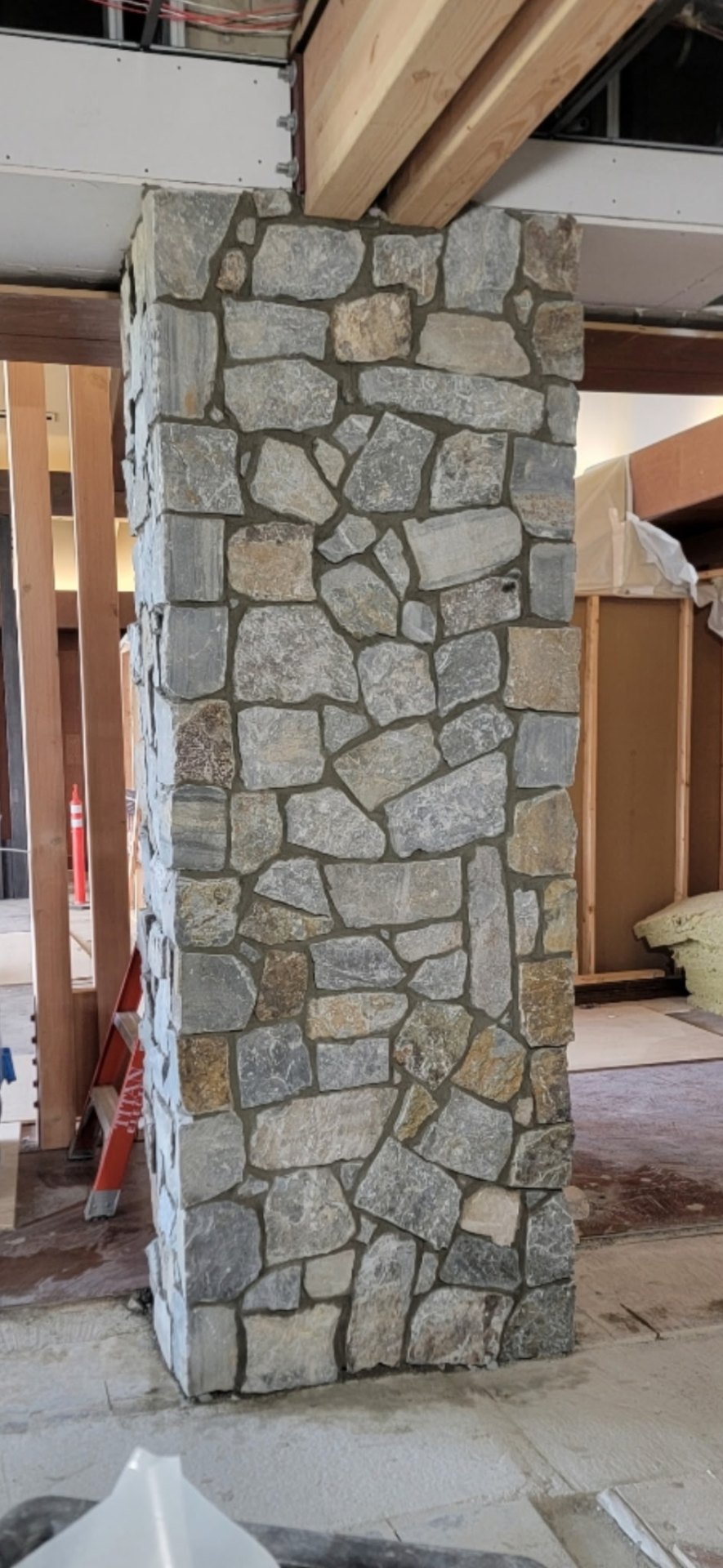 Interior structural column wrapped in mosaic-pattern natural stone veneer