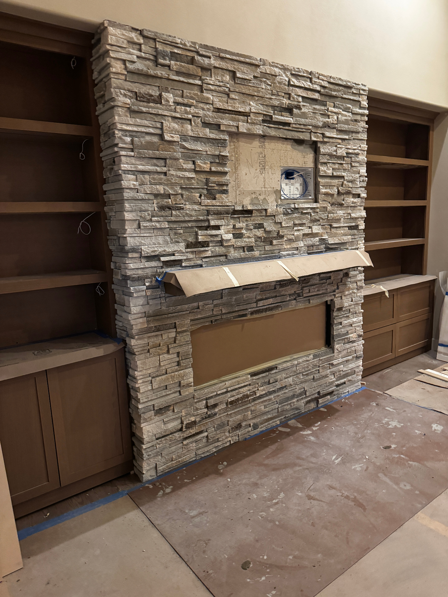 Stone veneer fireplace wall with built-in cabinetry